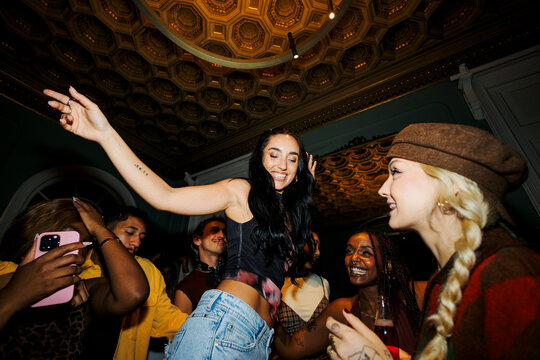 Diverse friends dancing together enjoying night party
