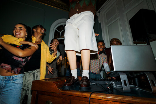 Young people dancing at a lively house party with a dj