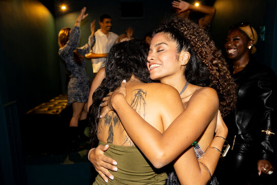 Best friends hugging in party at nightclub