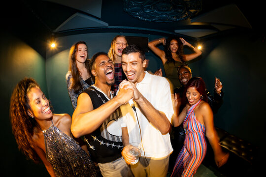 Diverse group of friends singing and dancing in karaoke