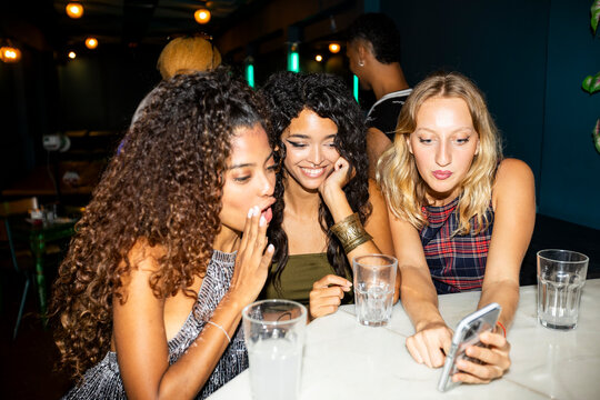 Group of girlfriends checking smartphone at nightclub party