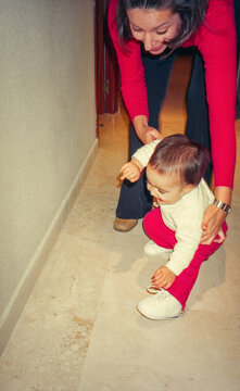 Analog photo of baby taking first steps with mother supporting