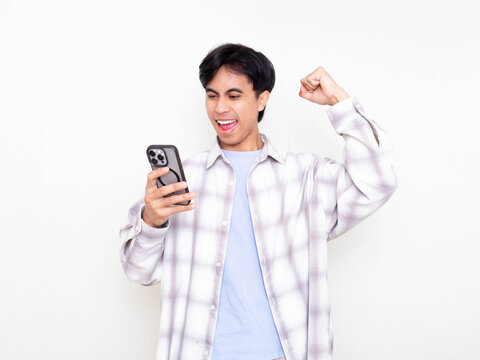 Young man celebrating while checking his smartphone, showing excitement about digital business results on a clean white background.