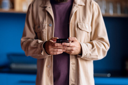 Casual Man in Beige Jacket Using Smartphone