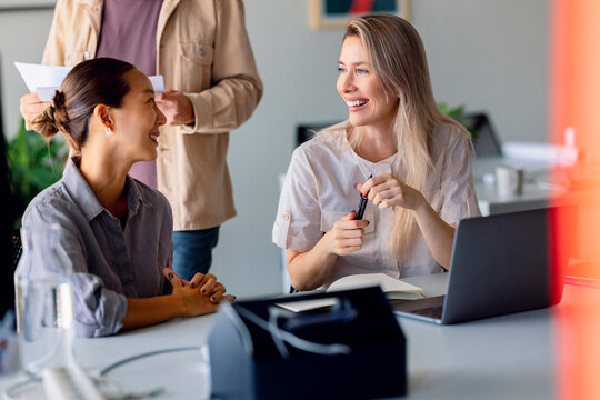 Business Meeting With Colleagues Laughing At Desk With Laptop