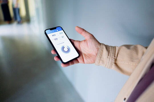 Smartphone With App On Hand In Modern Indoor Hallway Setting
