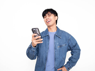 Young Asian man smiling while looking at his smartphone in a bright studio, ideal for advertising mobile apps, digital services, online communication, and positive user engagement.