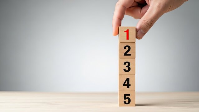 Hand placing number 1 block on top of stacked numbered wooden blocks concept