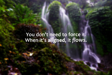 Life inspirational motivational quote - You don't need to force it. When it's aligned, it flows. On blur background of green nature waterfall in the forest. Faith and spirituality concept.