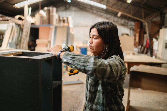Female Carpenter Assembling Furniture with Power Drill