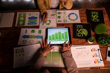 Business people discussing esg sustainability data on tablet and papers
