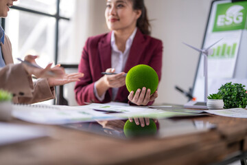 Businesswomen discussing esg strategy holding green earth globe