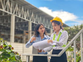 Women engineers discussing blueprint at construction site