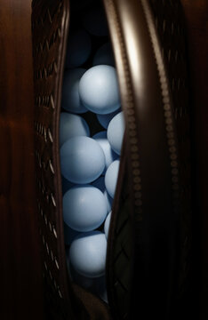 Blue ping pong balls packed in a brown carrying bag on a dark surface