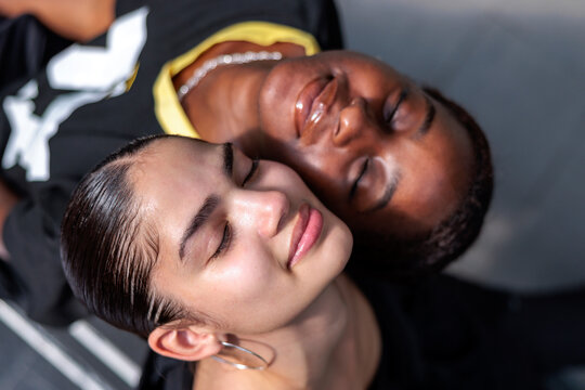Two women, eyes closed, heads together, peaceful and serene.