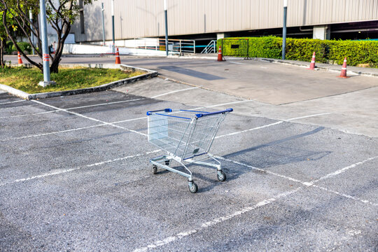 Abandoned shopping cart sits in empty parking lot.