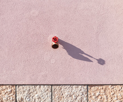 Red Metal Valve Casting Shadow on Textured Wall