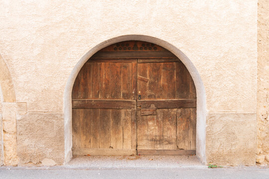 Rustic Wooden Arch Door in Weathered Stucco Wall