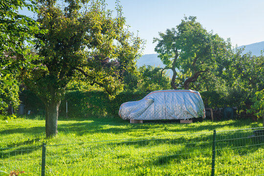 Covered Car in a Lush Garden Under Bright Sunlight