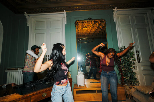 Young diverse women dancing, enjoying music at house party