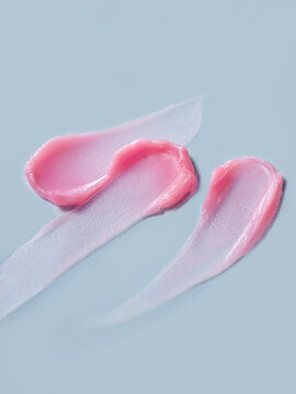 Pink lip balm swatches on a soft blue background