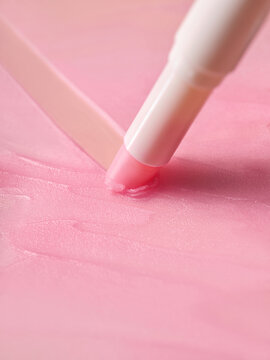 Lip balm application on a pink texture surface