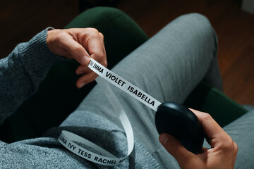 a man sitting on a chair observing a printed ribbon with baby names