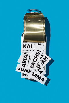 a metal tin can filled with printed baby names on a blue background