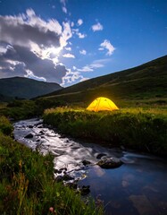 Illuminated tent by stream under starry sky