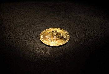Single Gold Bitcoin Coin on Dark Textured Surface Shiny Bitcoin Token Lying on Rough Black Background