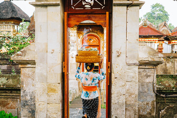 Balinese Woman Carrying Offering Basket Out of Temple Entrance