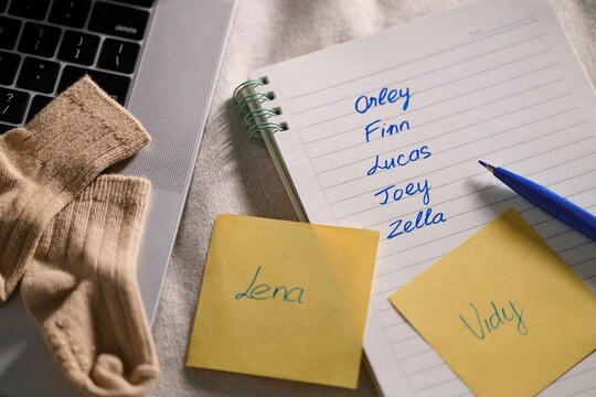 Baby name ideas on a notepad with a laptop and baby socks.