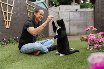 Young Man Plays With His Tuxedo Cat in the Backyard making it Stand