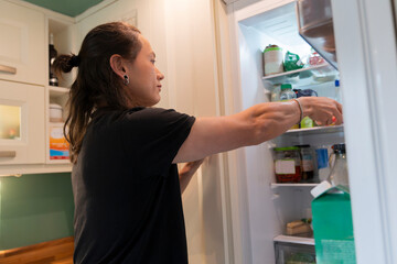 Young Man Searches for Fresh Ingredients in Home Kitchen Fridge