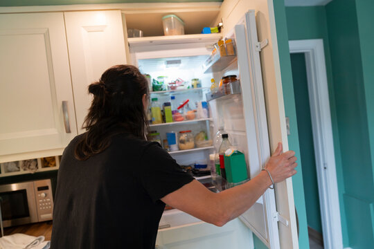Young Man Searches Fridge for Fresh Ingredients to Prepare Family Meal