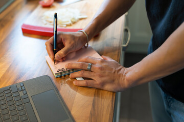 Young Man Creating a Grocery List in a Cozy Kitchen