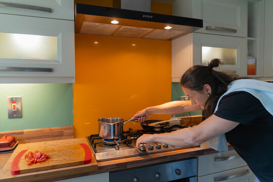 Young Man Cooks Pasta in Home Kitchen, lighting up the gas stove