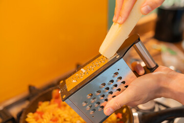 Anonymous Male Chef Grating Cheese on Pasta in Modern Kitchen detail