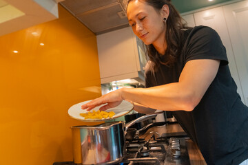 Young Man Cooks Pasta in a Modern Kitchen Using Whole Foods
