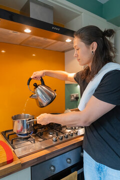 A Man Cooks Pasta pouring hot water in from the Kettle into the pot