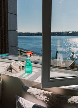 Spray Bottle and Cloth on Windowsill with Bright Lake View