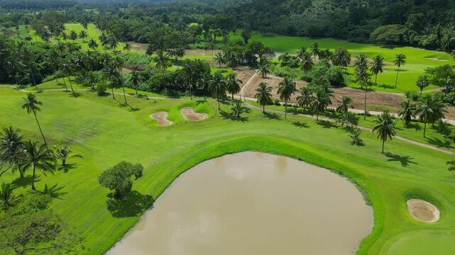 An elevated aerial surpassing a large water puddle within the landscaped grounds of Canlubang Golf and Country Club, revealing tropical greenery and scenic fairways in Calamba Laguna, Philippines
