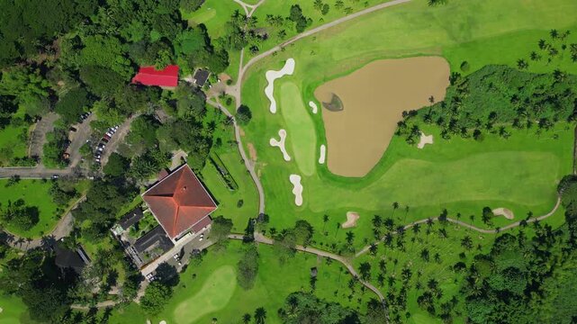 A circling downward top view aerial showcasing the expansive grounds of Canlubang Golf and Country Club, showing manicured fairways, water puddles, and tropical greenery in Calamba Laguna, Philippines