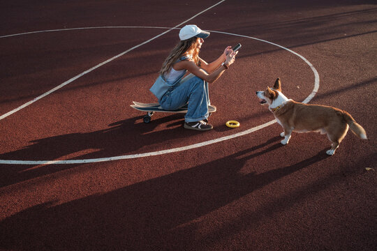 Girl playing with a corgi dog at a park during sunset