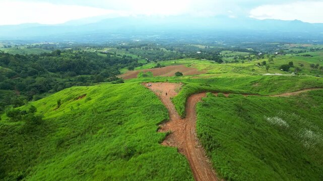 Elevated aerial showcasing winding dirt paths cutting through lush green hills and farmland patches, expanding to reveal the vast countryside in Quinawan mountain view, Mariveles Bataan, Philippines