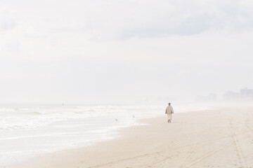 Woman walking along a misty beach near the shoreline