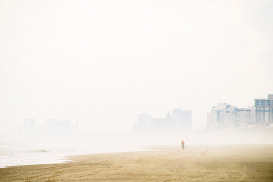 Bicyclist riding along a misty beach