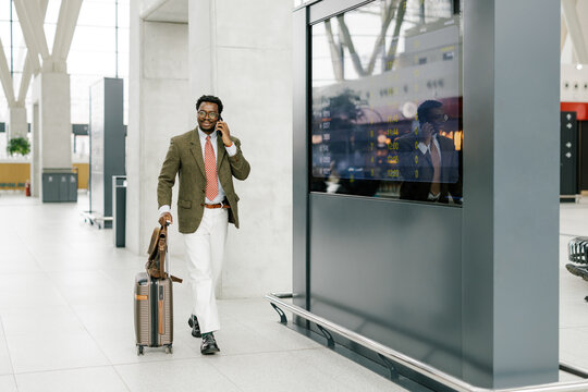 Businessman Walking Through a Modern Airport Terminal With Luggage