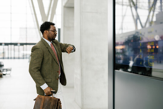 Businessman Checking Flight Schedule at Airport Terminal