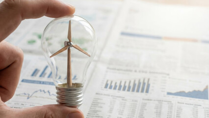 Sustainable investment concept with hand holding light bulb containing wind turbine symbolizing esg investing and ai driven financial growth